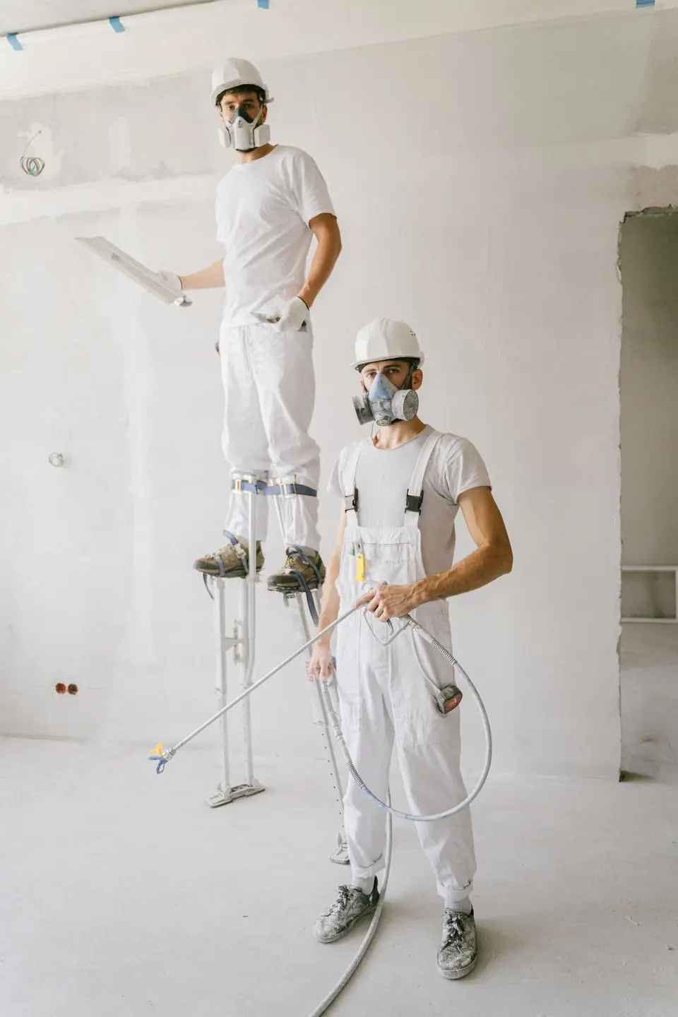 Deux artisans peintres en tenue blanche sur un chantier de rénovation