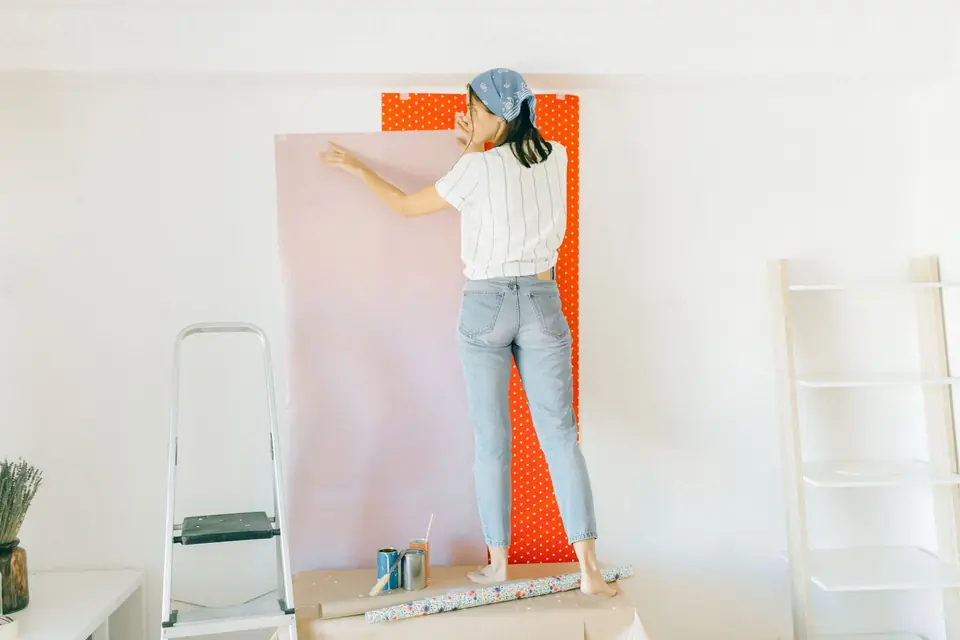 Pose d'un lé de papier peint intissé sur un mur de salon