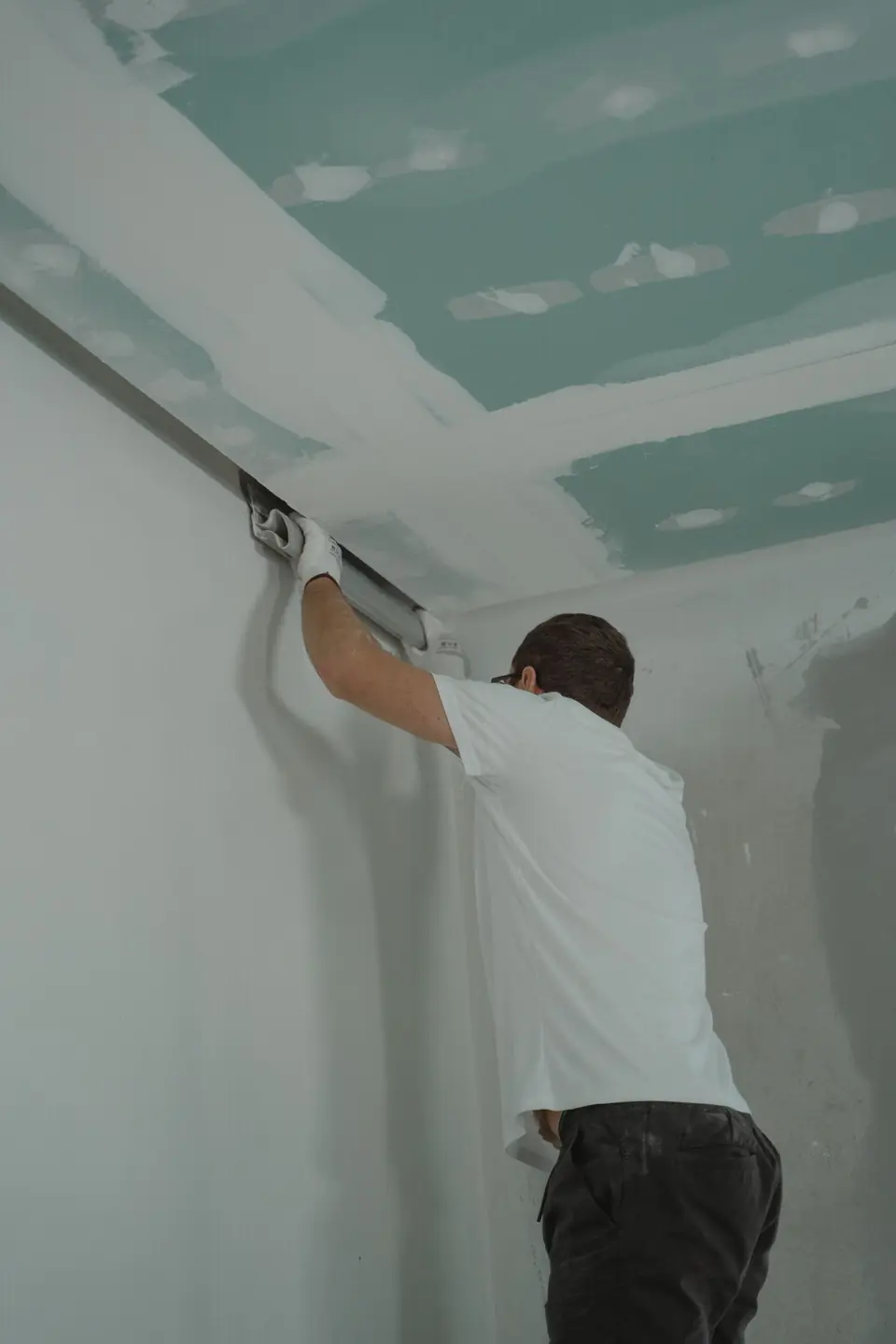Peintre traitant un plafond protégé par des bâches