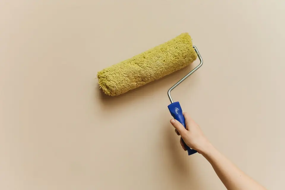 Artisan peintre appliquant la peinture au rouleau sur un mur intérieur