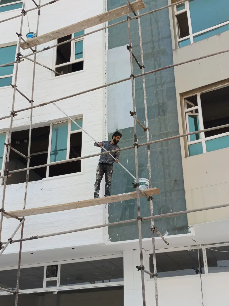 Façade de maison en cours de ravalement derrière un échafaudage